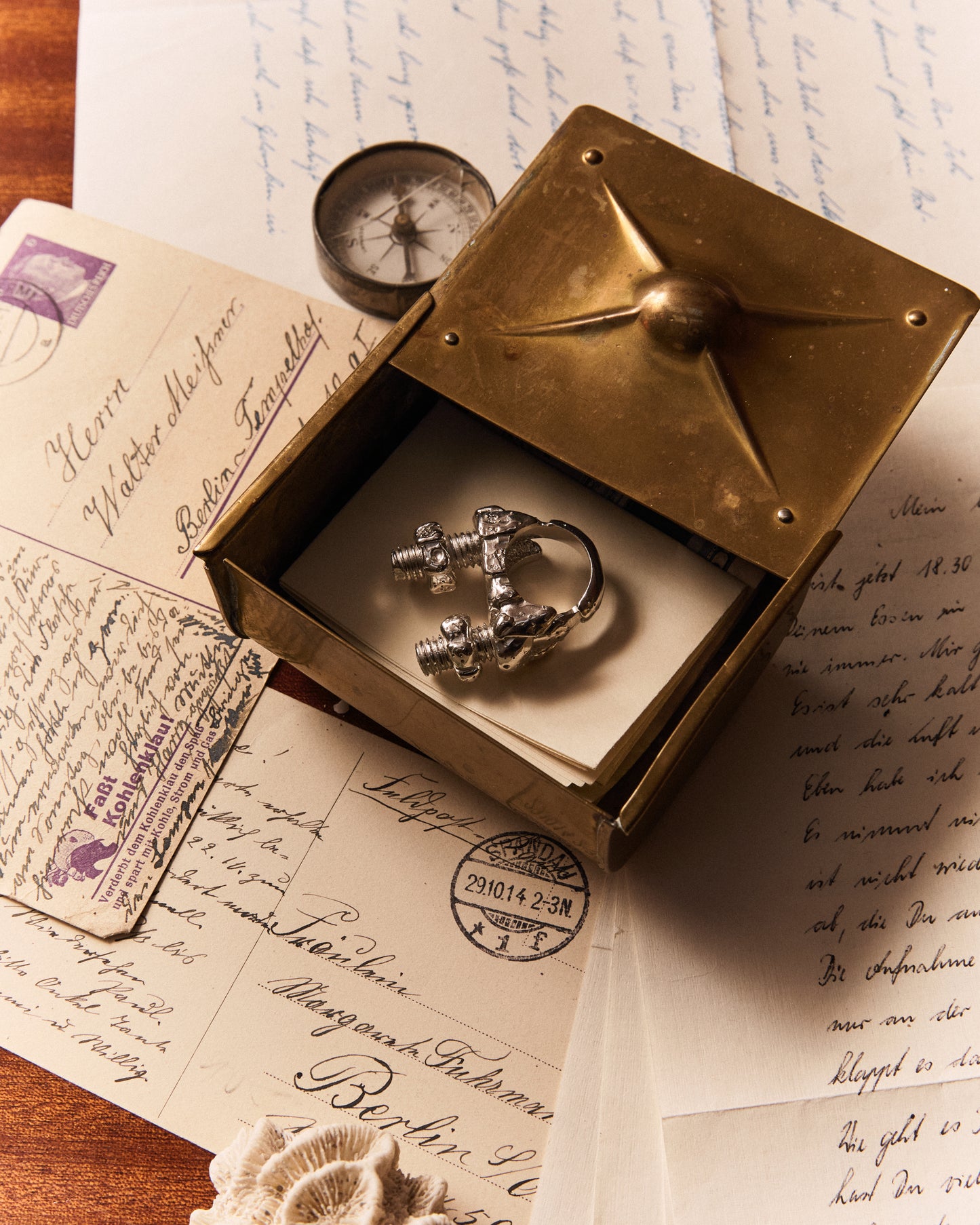 Maena Klemm Ring: robustes See-Artefakt mit texturierter, glänzender Oberfläche – Sterling Silber abgebildet im Kontext auf Navigationstisch