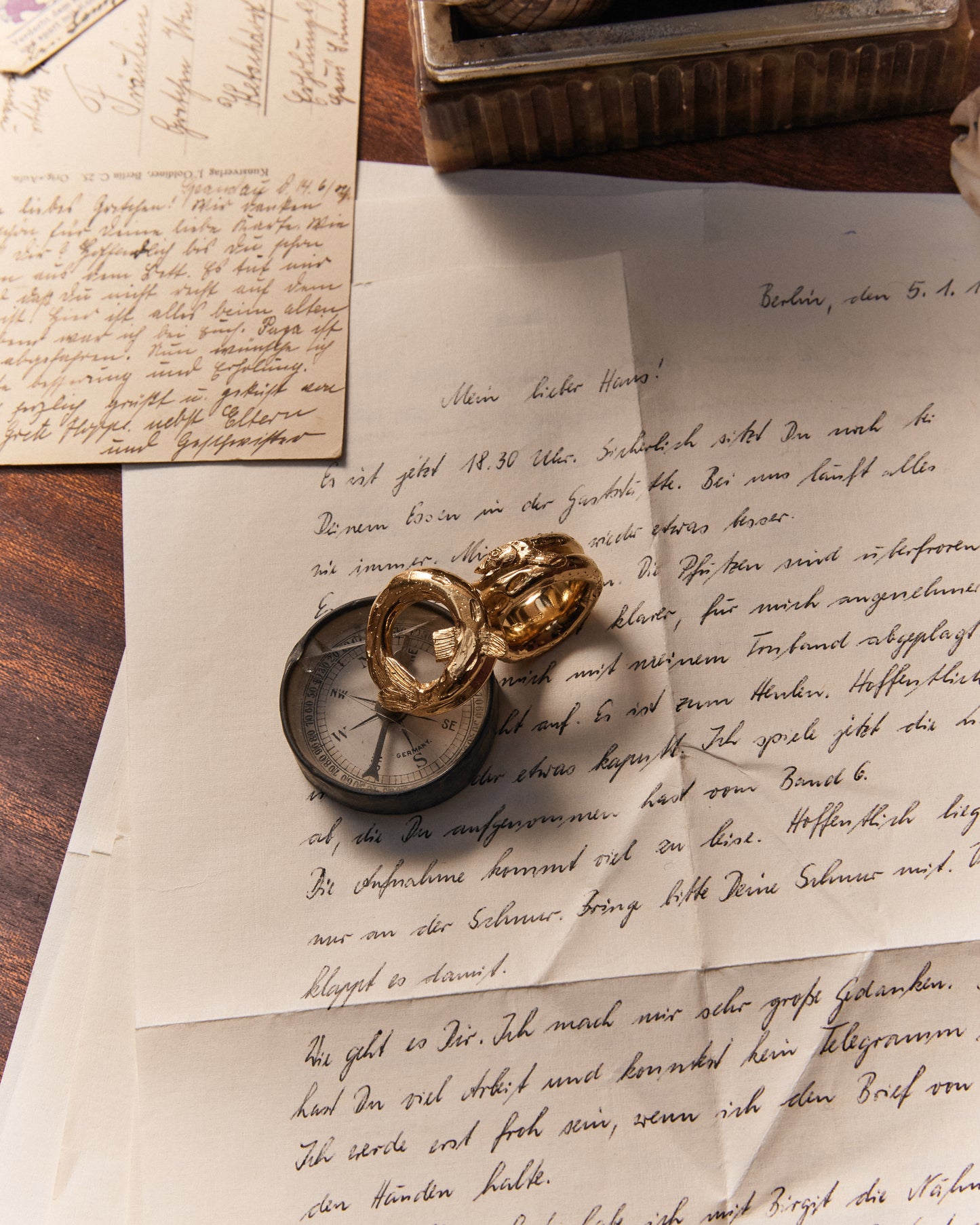 langer, marmorierter Zander schmiegt sich um den Finger. gold plattiert. Aufgenommen im Kontext auf Navigationstisch.