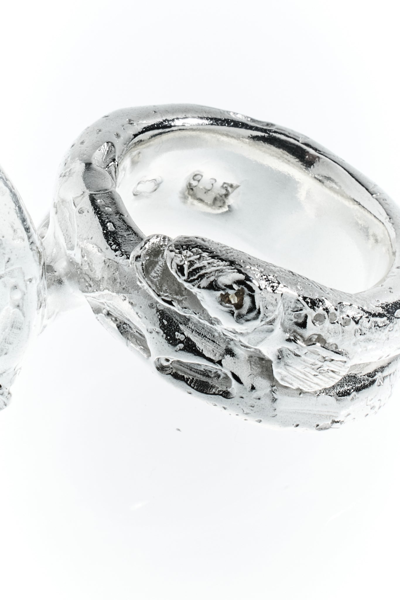 langer, marmorierter Zander schmiegt sich um den Finger. Sterling Silber. Detailfoto von Saphir Auge aufgenommen vor weißem Hintergrund.