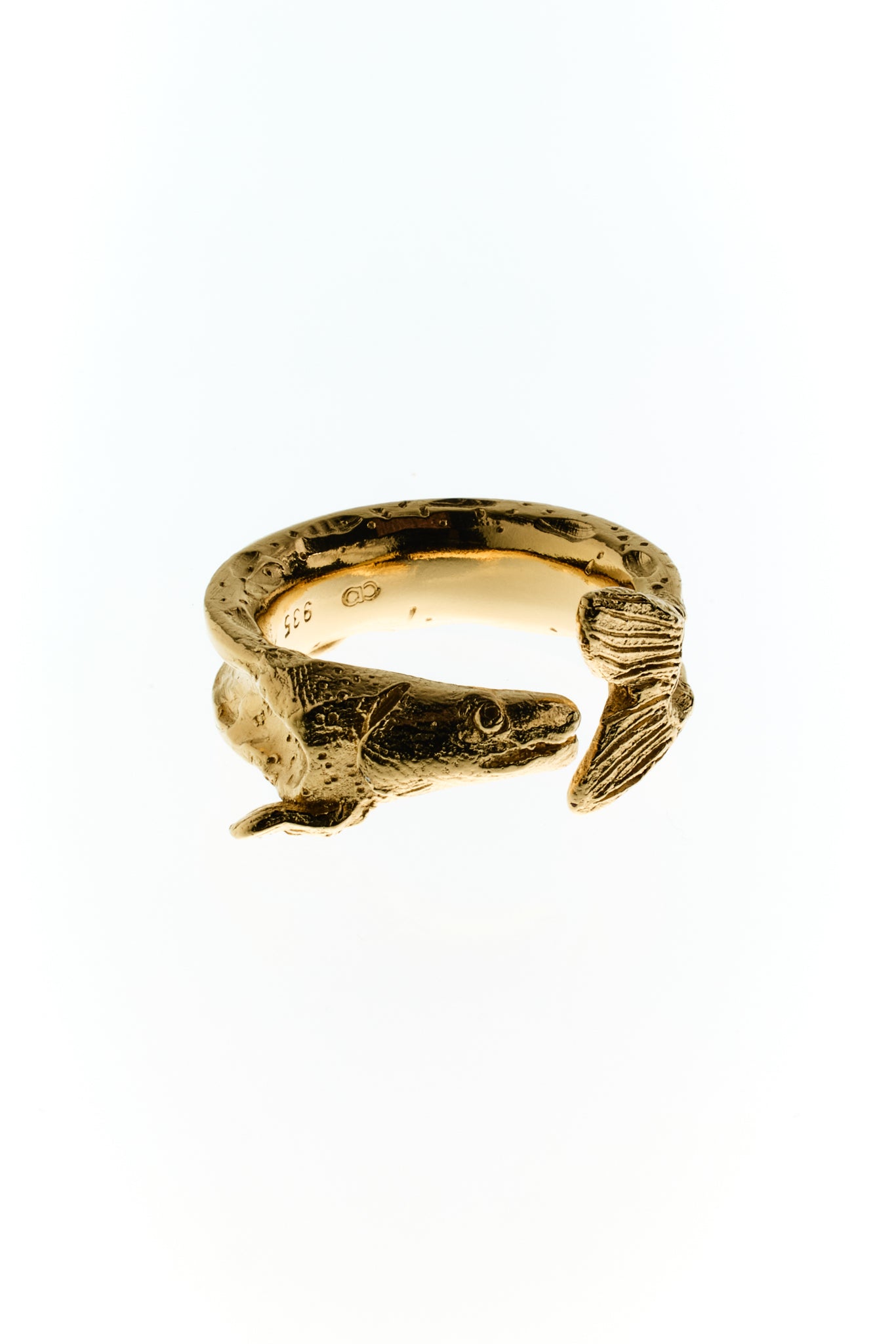 Zander um den Finger, marmorierte Haut gold plattiert. Abgebildet vor weißem Hintergrund.
