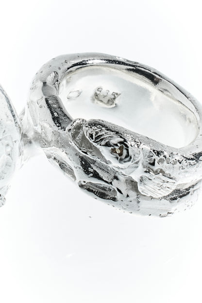 langer, marmorierter Zander schmiegt sich um den Finger. Sterling Silber. Detailfoto von Saphir Auge aufgenommen vor weißem Hintergrund.